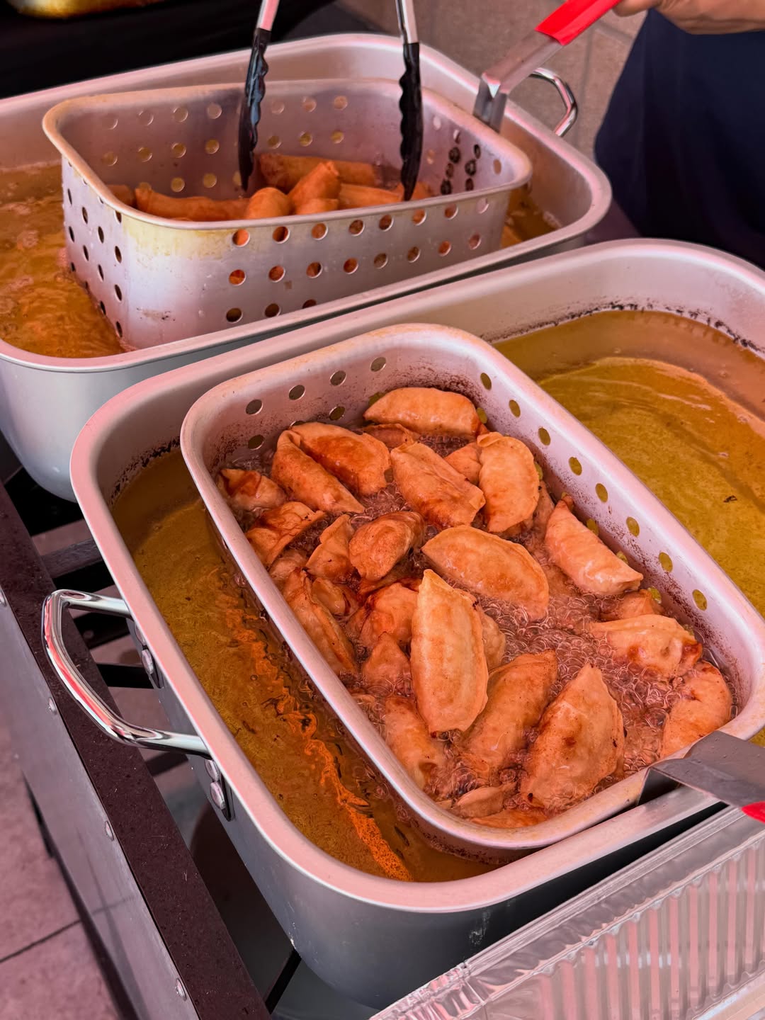 Two fryer baskets going at once, potstickers and egg rolls in hot oil